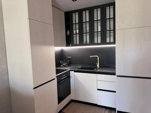 een keuken met witte kasten en een spoelbak bij Апартамент AZUR PREMIUM in Varna