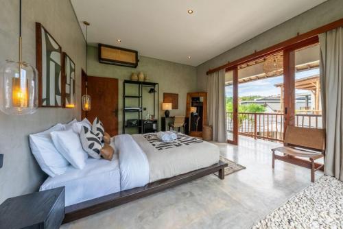 a bedroom with a large bed and a balcony at Kano Uluwatu in Uluwatu