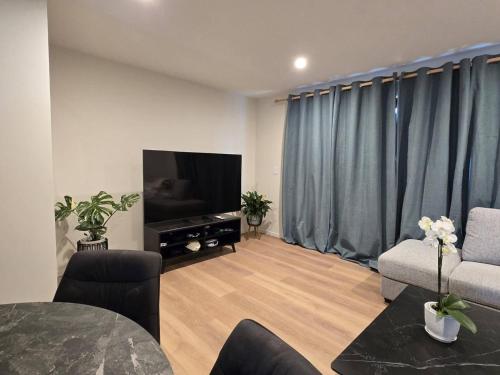 a living room with a flat screen tv and blue curtains at Double Bedroom in Newly Built Townhouse in Upper Hutt