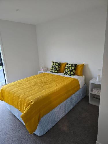 a bedroom with a bed with a yellow blanket on it at Double Bedroom in Newly Built Townhouse in Wallaceville