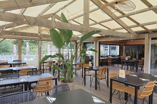 Un restaurante vacío con mesas y sillas y un techo grande. en Camping RCN Port l'Epine, en Trélévern