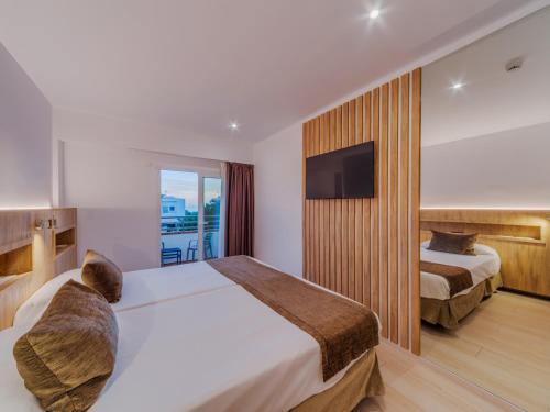 a hotel room with two beds and a flat screen tv at Hotel Principe Wellness&Spa in Playa de Palma