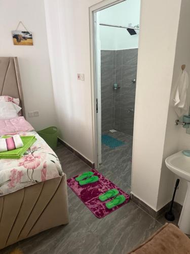 ein Schlafzimmer mit Dusche und einem Paar Hausschuhen in der Unterkunft PR Home Mtwapa Pride Apartments in Mombasa