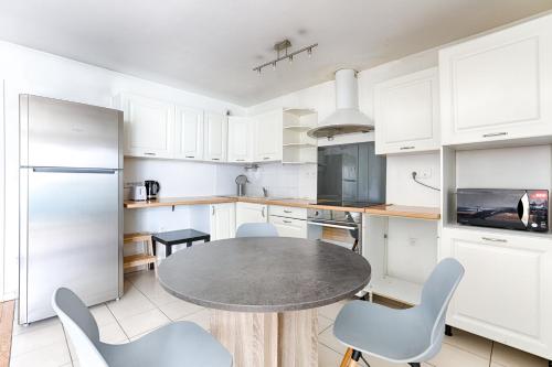 eine Küche mit weißen Schränken und einem Tisch und Stühlen in der Unterkunft Venturia - 23 min en train de Paris in Le Plessis-Bouchard