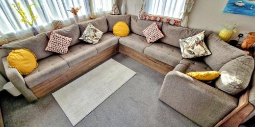 ein Wohnzimmer mit einer Couch mit Kissen darauf in der Unterkunft Trieste, 2 Bedroom, 6 Berth Caravan, Seasalter in Seasalter