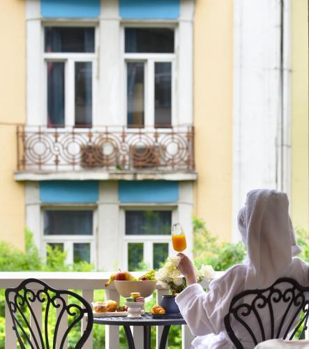 a woman sitting at a table with a glass of wine at The Oscar Olympic Hotel in Thessaloniki