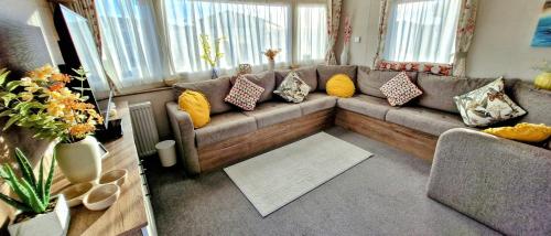 ein Wohnzimmer mit einer Couch mit Kissen darauf in der Unterkunft Trieste, 2 Bedroom, 6 Berth Caravan, Seasalter in Seasalter