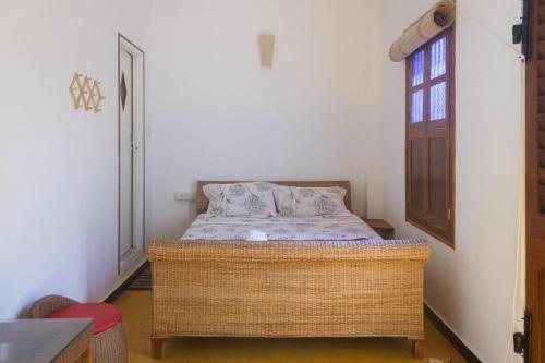 FRENCH RIVERA Heritage Boutique Villa في بونديتْشيري: غرفة نوم مع سرير الخوص في غرفة