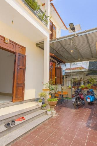 a porch of a house with a door and a motorcycle at Sim House in Hue