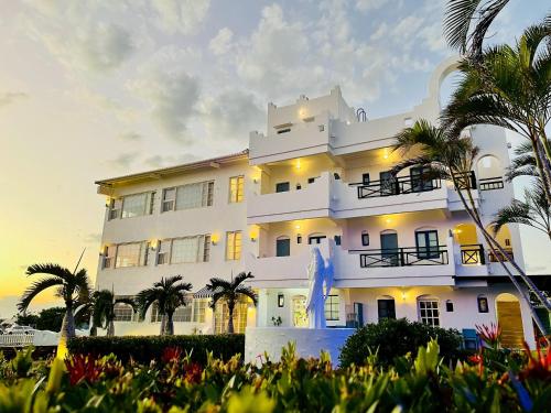 a white building with palm trees in front of it at Canaan B&B Kenting in Eluan