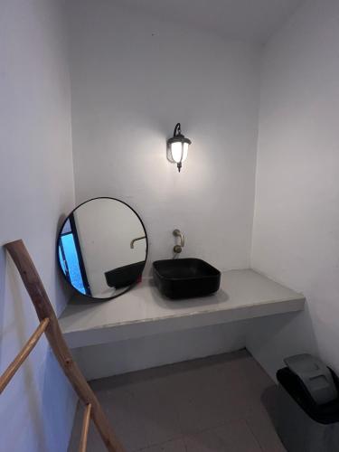 a bathroom with a sink and a mirror on a shelf at Pinggan harmoni in Baturaja