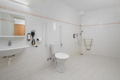 a white bathroom with a toilet and a sink at Hotel Arena Liberec in Liberec