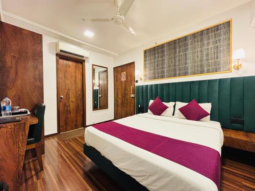 a bedroom with a large bed with red pillows at J Hotel and Banquets in Mumbai
