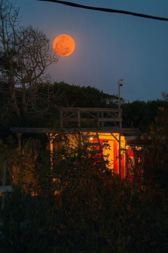 an orange moon rising over a building at dusk at Luna roja in Punta Del Diablo