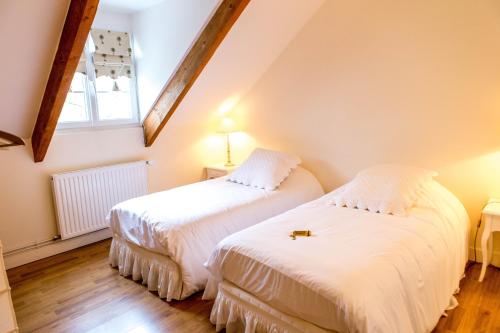 two beds in a attic room with a window at Domaine de la Croix Tibi in Guilly