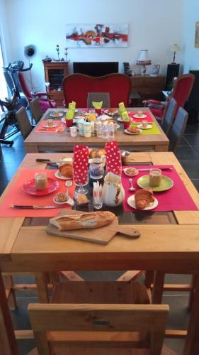 een houten tafel met borden met eten erop bij Chambre d'hôtes du Cerisier in Noyers
