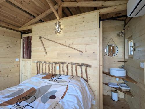 a log cabin bedroom with a bed and a sink at "La cabane", la roseraie de Zoubiroux in Saint-Geneys-près-Saint-Paulien