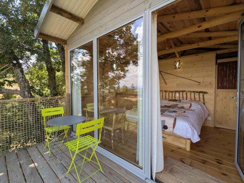 a room with a bed and a table on a deck at "La cabane", la roseraie de Zoubiroux in Saint-Geneys-près-Saint-Paulien