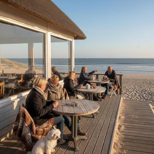 a group of people sitting at tables on the beach at Affordable Private BedRoom Near the Beach in Zoutelande