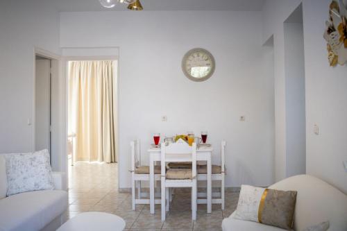 a white living room with a table and a clock at Fotis House 3 in Afantou