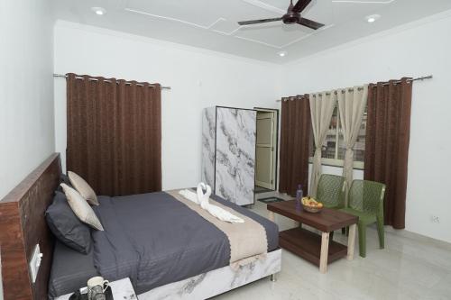a bedroom with a bed and a table and a ceiling fan at Taposthalam Sacred Retreat Hotel in Rishikesh in Rishīkesh