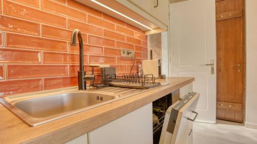 a kitchen with a sink and a brick wall at Alkyoni luxury apartments Katakolo in Katakolon