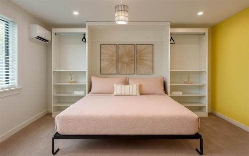 Garden of Manors - Boutique Guesthouse in Florida في فورت لاودردال: غرفة نوم بسرير وردي الشراشف والرفوف