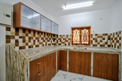 a kitchen with wooden cabinets and a window at Hotel Eyokar Goa in Candolim