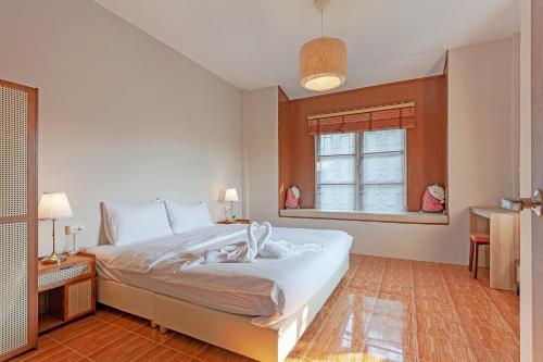 a bedroom with a large white bed and a window at The Galvis Pool Villa - Boutique Stay Near Na Jomtien Beach in Na Jomtien