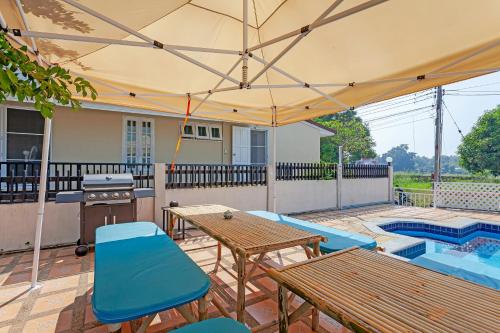 a patio with tables and chairs and an umbrella at The Galvis Pool Villa - Boutique Stay Near Na Jomtien Beach in Na Jomtien