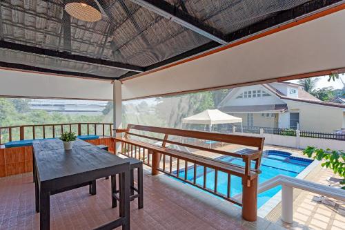 a balcony with a table and a swimming pool at The Galvis Pool Villa - Boutique Stay Near Na Jomtien Beach in Na Jomtien