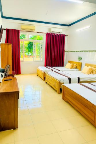 three beds in a room with red curtains and a desk at Yến Ánh Xuân Hotel in Phan Rang–Tháp Chàm