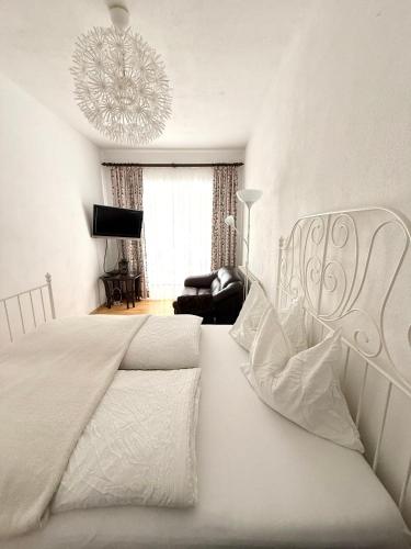 a white bedroom with a bed and a chandelier at Traumhafte Wohnung auf Pferde Ranch in Aich