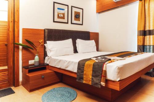 a bedroom with a bed with a wooden headboard at Merlot Suites in Porvorim