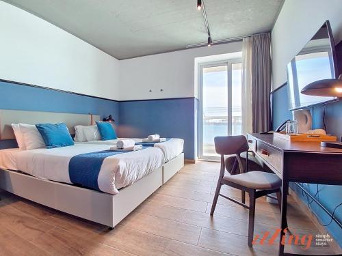 a bedroom with a bed and a desk and a computer at South 32 Hotel by Zzzing in Birżebbuġa