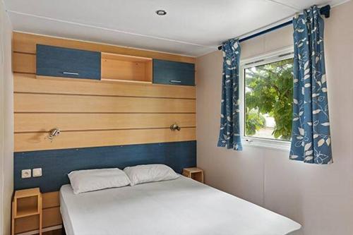 a bedroom with a white bed and a window at Camping Clos Cottet in Angles
