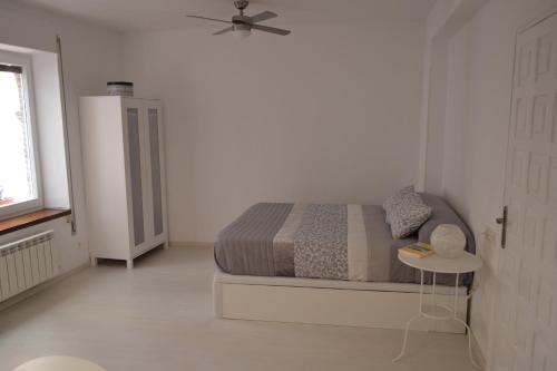 a white bedroom with a bed and a table at Minimal Apartamentos in Tudela