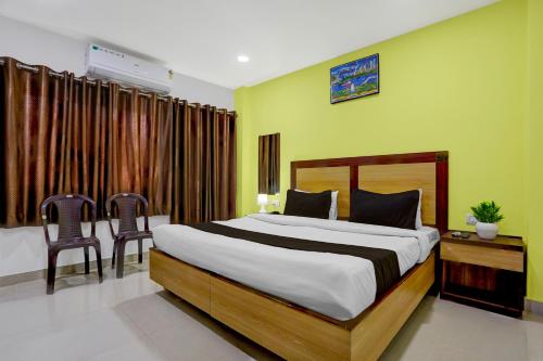 Hotel O Varanasi Trade Center formerly Vairaghi Villa في فاراناسي: غرفة نوم بسرير كبير وكرسيين