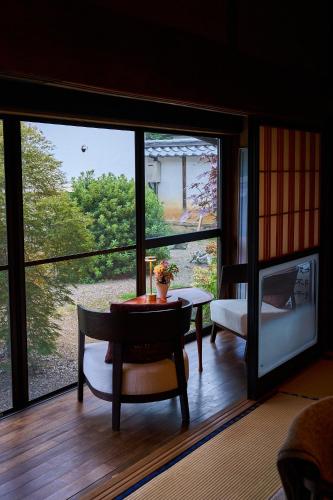a living room with a table and a large window at 1日1組限定の宿 旅館 土と糸 Ryokan Tsuchi to Ito in Omi