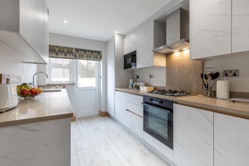 a kitchen with white cabinets and a stove top oven at Stanley House in Reading