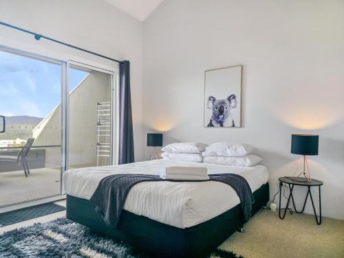 Un dormitorio con una cama y una ventana grande. en Cascades 15 - Amazing Lake Views l Spa Bath l Split Level Apt l Central Location l Wi-Fi, en Jindabyne