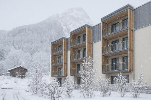 a building covered in snow with a mountain in the background at Le Mallet, Courmayeur, Alpine Homesuite in Courmayeur