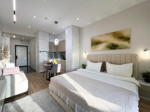 a bedroom with a large white bed and a kitchen at NRG U- Tower in Tashkent