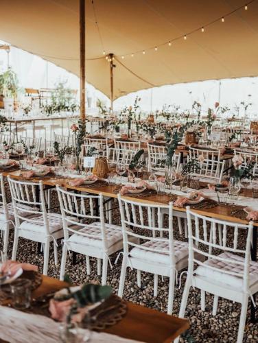 Una mesa preparada para una boda con sillas blancas. en GreenValleyGlamping, en Šešče pri Preboldu