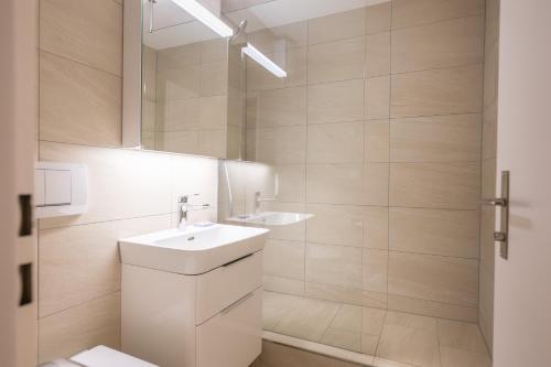 a white bathroom with a sink and a mirror at Zuhause in den Alpen Ihre Ferienwohnung mit Hallenbad und Sauna in Lenzerheide