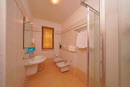 Un baño con dos inodoros, un lavabo y una ducha. en Residence Besass, GTSGroup, en Tignale