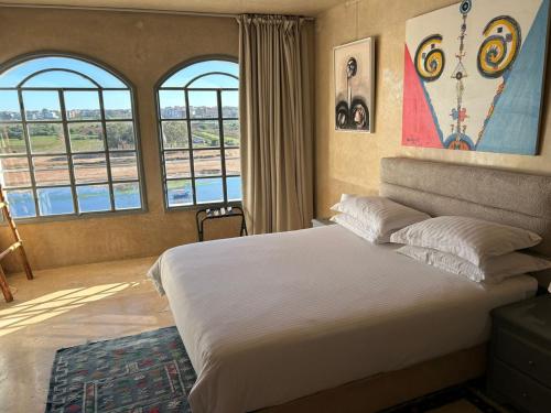 a bedroom with a large bed with two windows at L'Oum Errebia in Azemmour