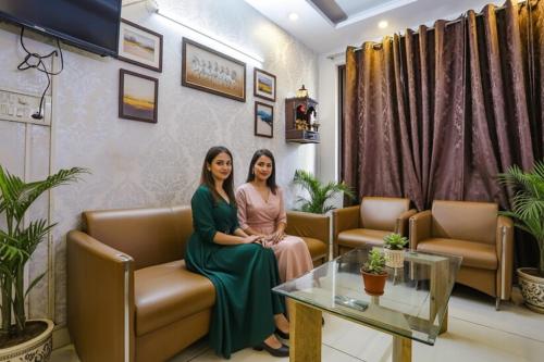 two women sitting on a couch in a waiting room at FabHotel Comfirt Inn in Noida