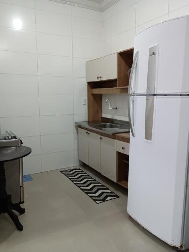 einen weißen Kühlschrank in einer Küche mit einem Tisch in der Unterkunft Casa bananeira in Bombinhas