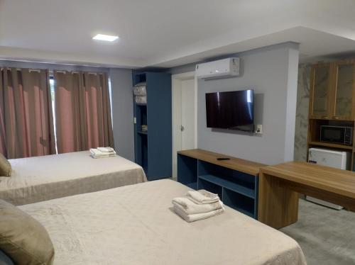 Una habitación de hotel con dos camas y un televisor de pantalla plana. en Apart hotel Corbari, en Ametista do Sul